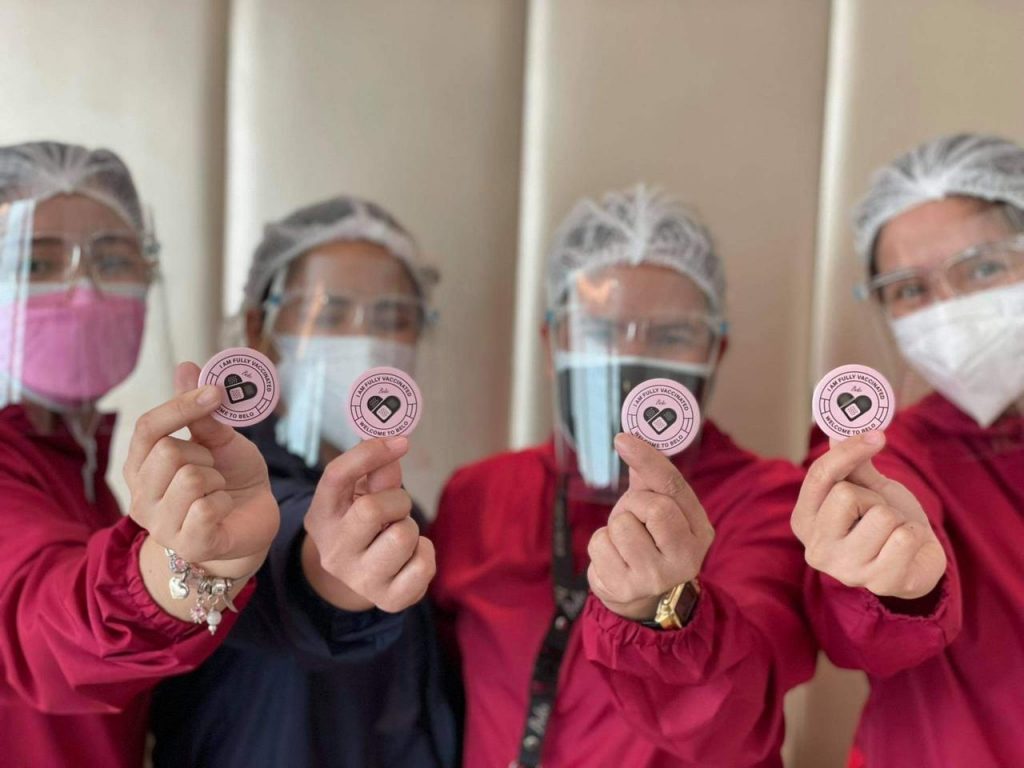 Belo Staff holding i am fully vaccinated pins